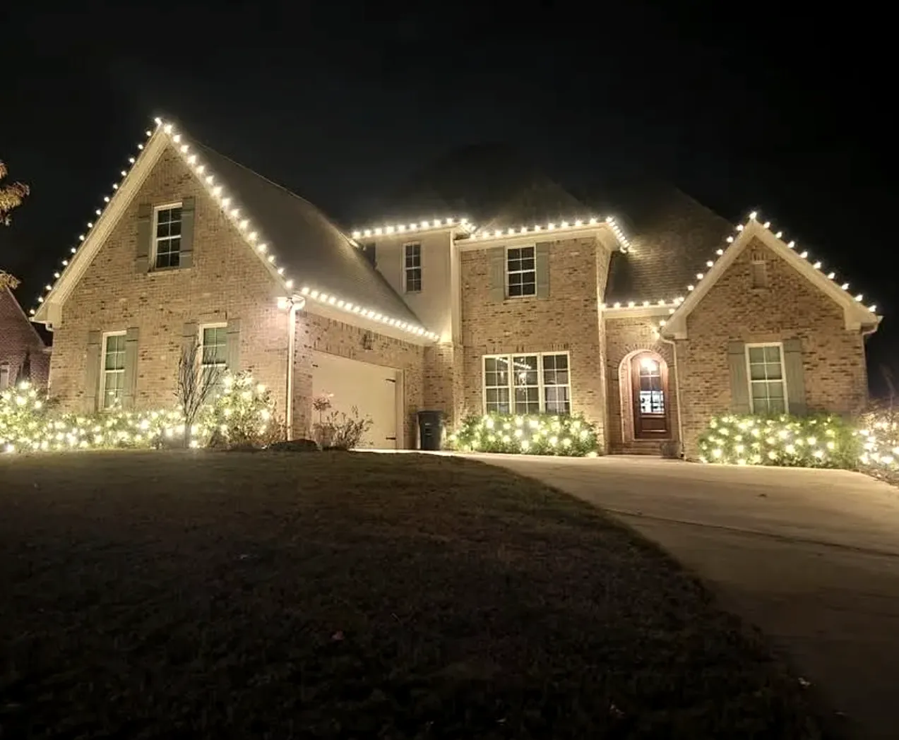 Brick home with twin gables and bright wrapped shrubs along the front beds.