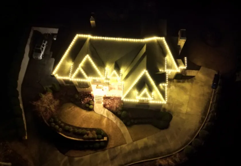 Aerial view of a roof with the gable triangles and ridge lines traced in warm light.